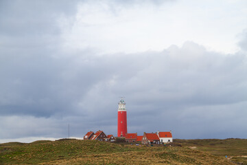 The lighthouse Eierland and some white houses with read tiled roofs in the dunes on the Dutch island Texel in the Wadden sea