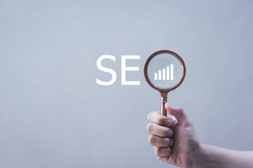 SEO Search Engine Optimization, Businessman holding through magnifying glass with text SEO, concept for promoting ranking traffic on website, optimizing your website to rank in search engines.