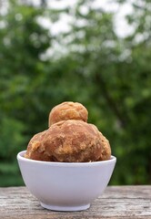 Closeup of  Organic Palm Jaggery or Gur in a White Bowl Isolated on Wooden Table in Vertical Orientation