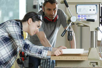 young technicians working on pillar drilling machine in workshop