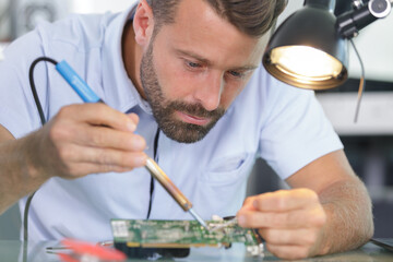 man with a soldering iron repairs computer equipment