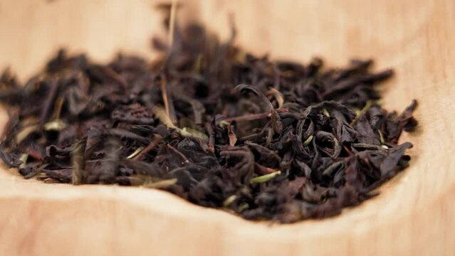 Dried black tea leaves with thyme herb in rustic wooden bowl. Dry healthful herbal healing ingredient. Rotation
