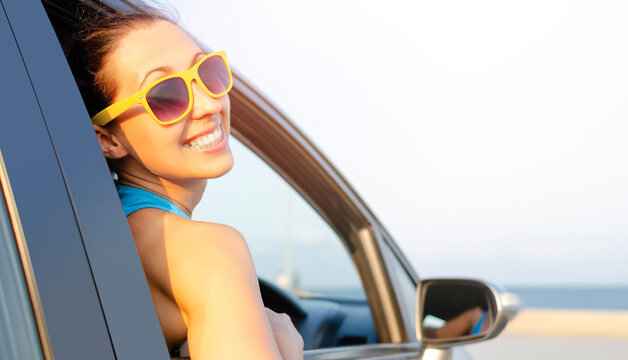 Beautiful girl in a car smiling on a background of blue sea.
