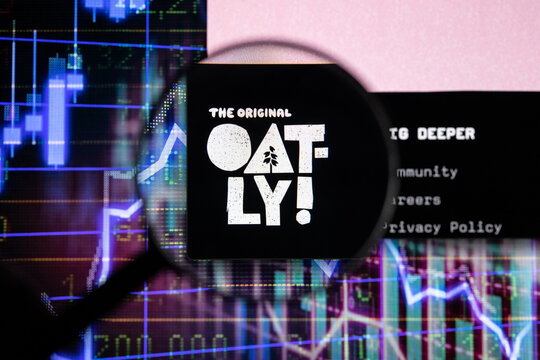 Oatly! company logo on a website with blurry stock market developments in the background, seen on a computer screen through a magnifying glass