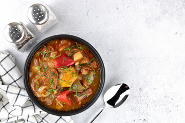 Khashlama - meat stew of beef or lamb meat with vegetables and spices on a gray background. Armenian and Georgian cuisine. Top view, copy space.