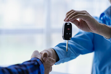 Closeup of car sale and buyer shaking hands Car salesman gives keys to buyer Close-up of car...