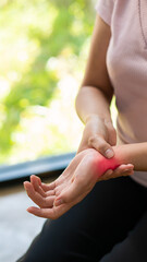 Woman having numbness wrist pain or Carpal Tunnel Syndrome holding her aching hand near young woman left wrist pain syndrome office health care concept vertical image