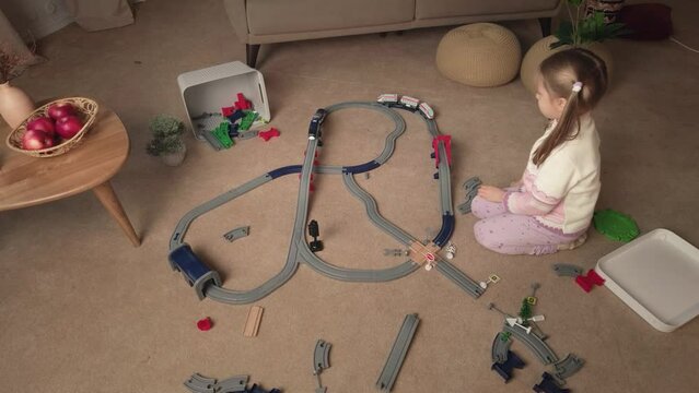 Little girl play with railroad and toy train at home