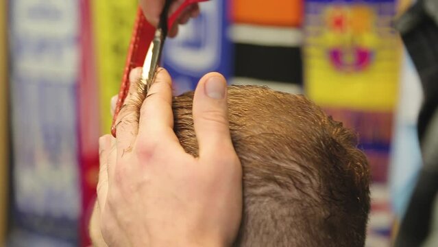 Barbershop. Men's haircut in detail. Close-up of a barber's hand. Barbershop. The man is doing a haircut. Close-up master's tools, comb, scissors, trimer.