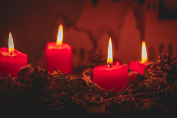 Vier brennende Adventskerzen auf Adventskranz Nahaufnahme mit weihnachtlicher Dekoration im...
