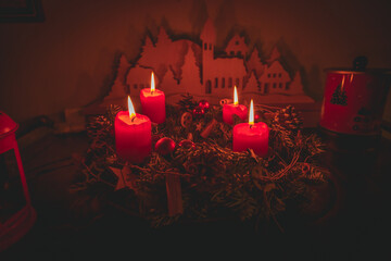 Vier brennende Adventskerzen auf Adventskranz mit weihnachtlicher Dekoration