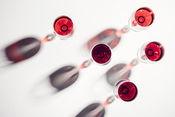 Glasses of red wine with shadows on a white background.