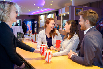 young people being served popcorn and drinks at cinema