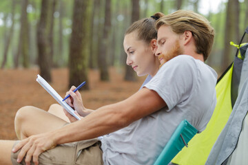 couple writing a list next to a tent