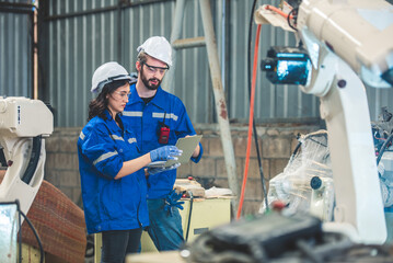 Engineers team mechanic using computer controller Robotic arm for welding steel in steel factory...