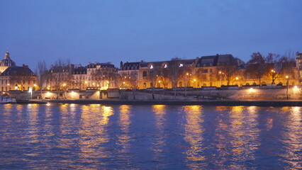 Promenade au bord de la Seine pendant une soirée, début saison d'automne, éclairé par des lampadaires urbaines jaunes, lumière reflétant sur l'eau