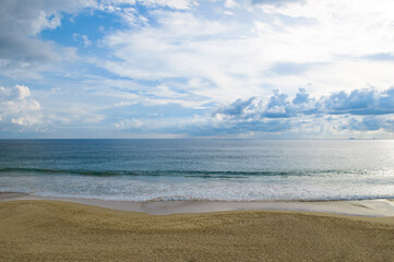 Tropical sandy beach, azure ocean and blue cloudy sky.