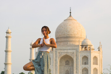 Girl doing yoga in front of the Taj Mahal, doing the Tree pose.