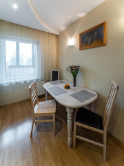 Modern interior of kitchen. Table and chairs. Window with tulle. No people.