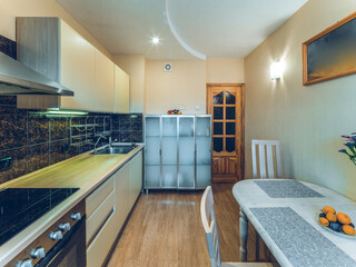 Modern simple interior of kitchen. White table and chairs. Sink and oven. Wooden door.