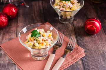 Olivier salad in bowls and Christmas decorations on a wooden table