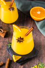 Homemade hot orange grog with cardamom and cinnamon in glasses on the table. Vertical view