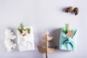 Furoshiki with fir branches, cones, knitted and cardboard spruces on a light background.