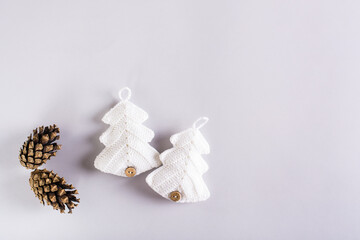 Two knitted fir trees and pine cones on a gray background. Handmade Christmas decor
