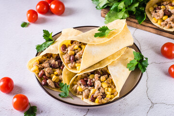 Traditional mexican burritos with minced meat, corn and beans on a plate on the table