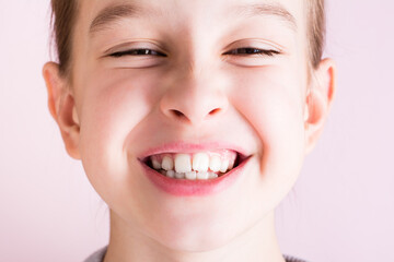 Portrait of a girl with crooked teeth on a pink background. Dentistry and orthodontics