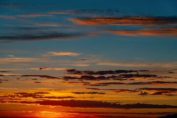 Fototapeta na wymiar Horizontal cloud formations at sunset stretch across the sky