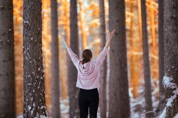 Kobieta medytująca o zachodzie słońca w zimowym lesie - obrazy, fototapety, plakaty