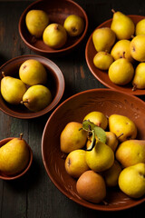 juicy homemade pears in clay plates on dark background in rustic style.