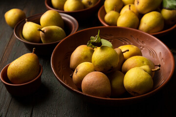 Delicious homemade pears in clay plates on dark background in rustic style.
