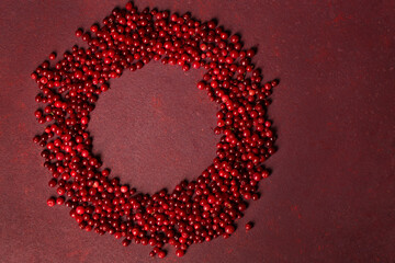 lingonberries are scattered in the shape of a circle on a burgundy background