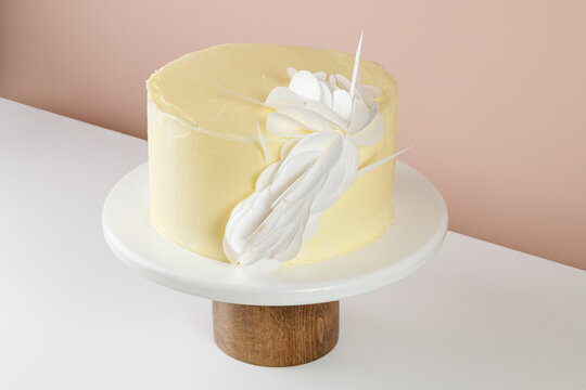 Cake with cream decorated with Wafer Paper, sheets on white wooden cake stand on beige background, copy space.