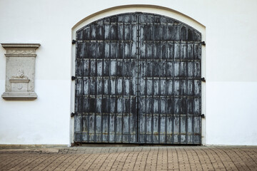 Ancient grey wood and iron gate portal in white modern wall