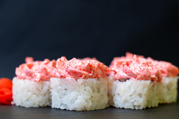 Japanese food. Sushi on a black background. Roll with rice on top with a cap of caviar.