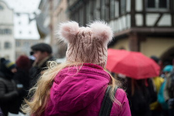 Closeup of young woman wearing a pink woolen hat in the street