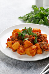 Goulash, beef stew with potatoes. Stewed meat with green parsley on white plate. Dinner, dish..