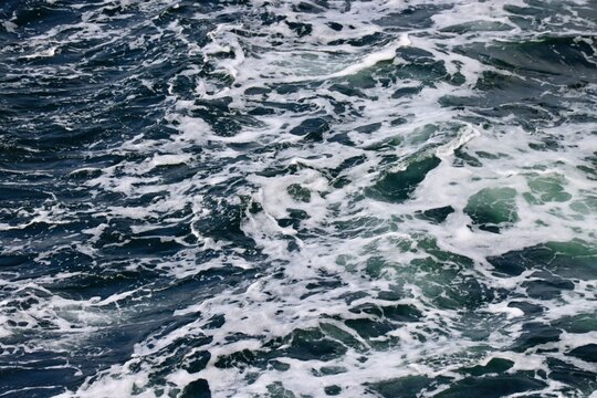Stern waves with white foam tips on greyish blue sea water, photo taken from aboard ship. Selective focus © Ilona Lablaika