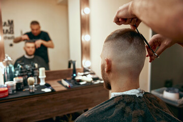 hairdresser does hairstyle with scissors in barber shop