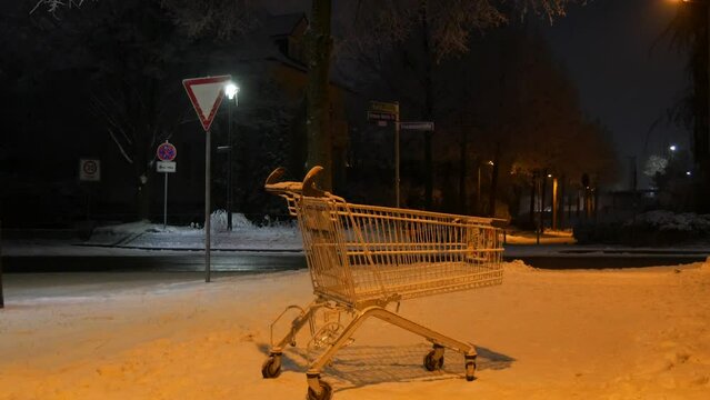 An empty cart from a supermarket on the street on a dark winter evening in the light of lanterns