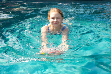 Fototapeta na wymiar Smiling teenager girl swimming in the pool