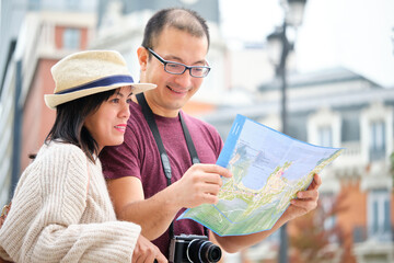 Happy multi-ethnic traveler couple sightseeing city with map. Tourism in Madrid, Spain.