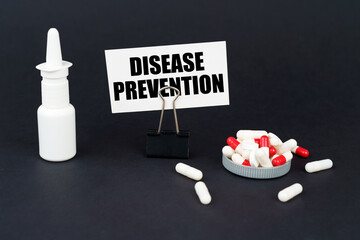 On a black surface are pills, a nasal spray and a paper sign with the inscription - DISEASE...