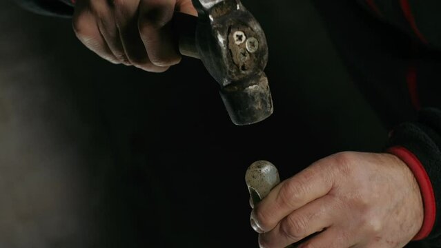 Hands of a sculptor with a hammer and blows isolated on a black background. Media. Close-up of work with a chisel.