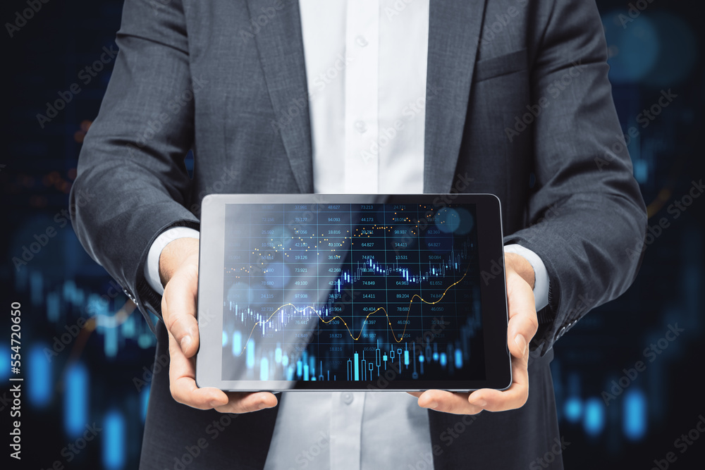 Poster close up of businessman hands showing tablet with glowing forex index chart/graph on dark background