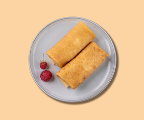 Homemade roll crepes with raspberry on a plate on a yellow background. Healthy food concept.