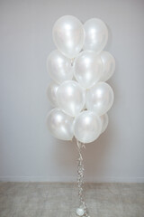 a bouquet of white mother-of-pearl balloons on a gray wall background